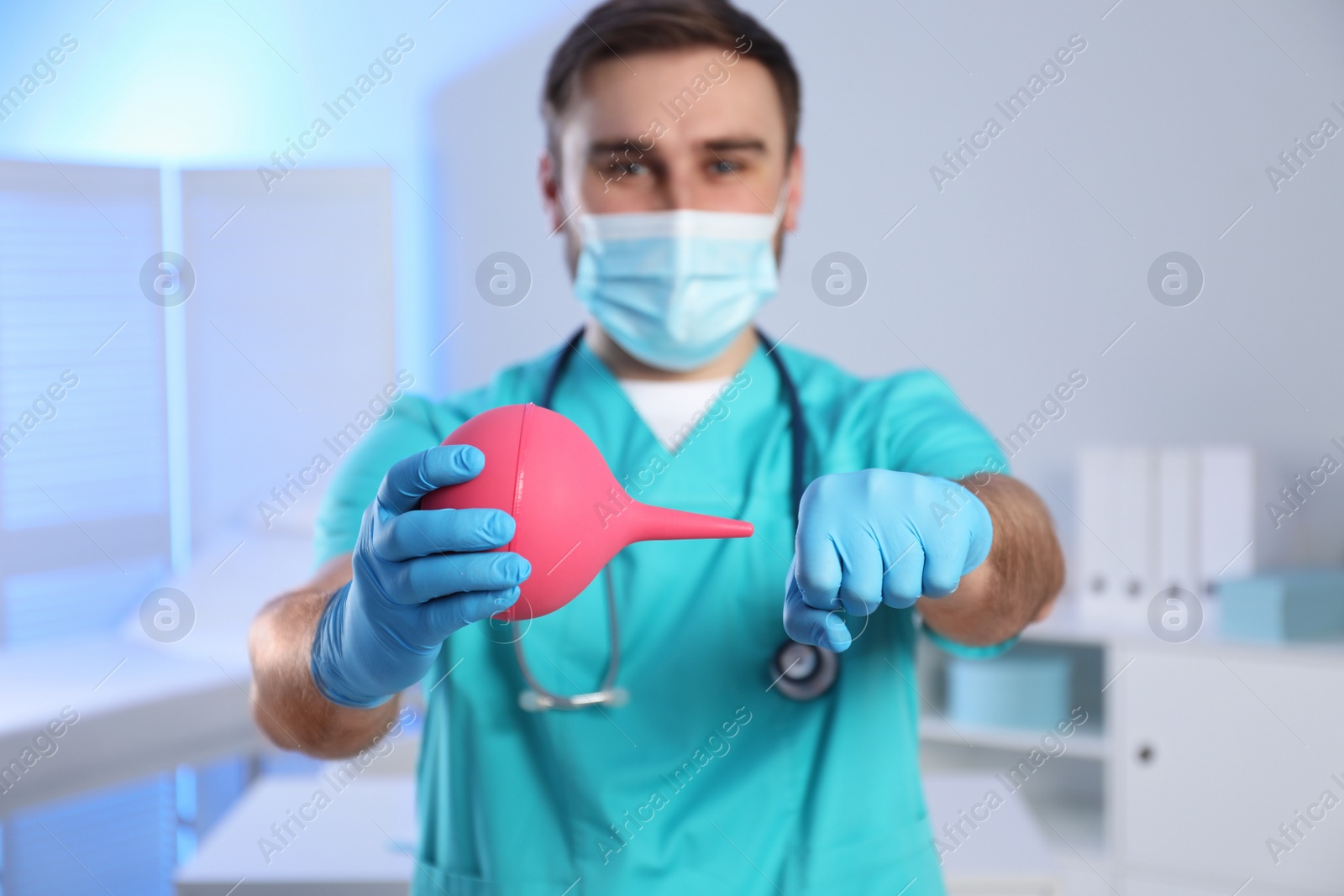 Photo of Doctor demonstrating usage of enema in examination room, focus on hands