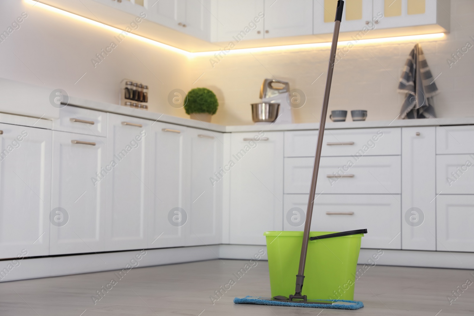 Photo of Bucket and mop on floor at home, space for text. Cleaning equipment