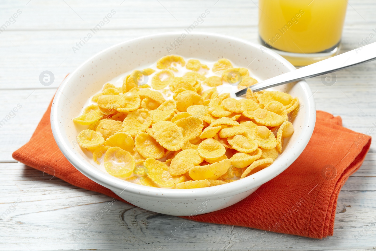 Photo of Tasty corn flakes with milk on white wooden table