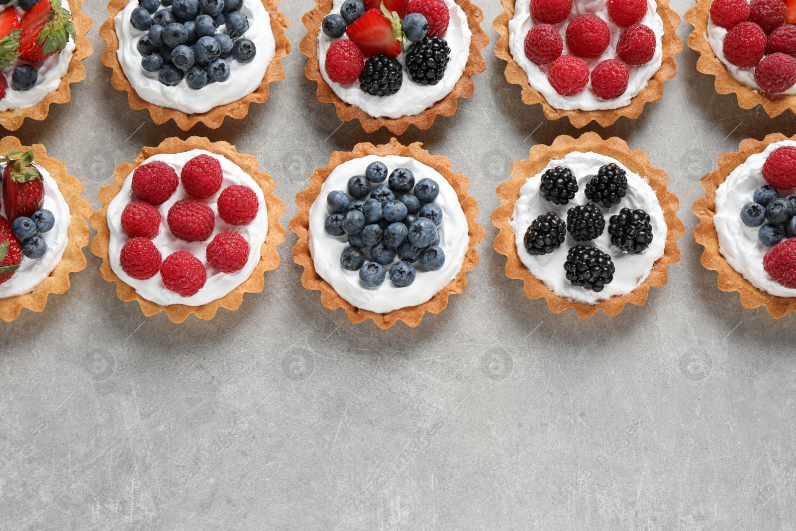 Photo of Many different berry tarts on table, flat lay with space for text. Delicious pastries