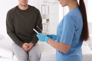 Photo of Doctor taking sample for STD testing from man in clinic, closeup