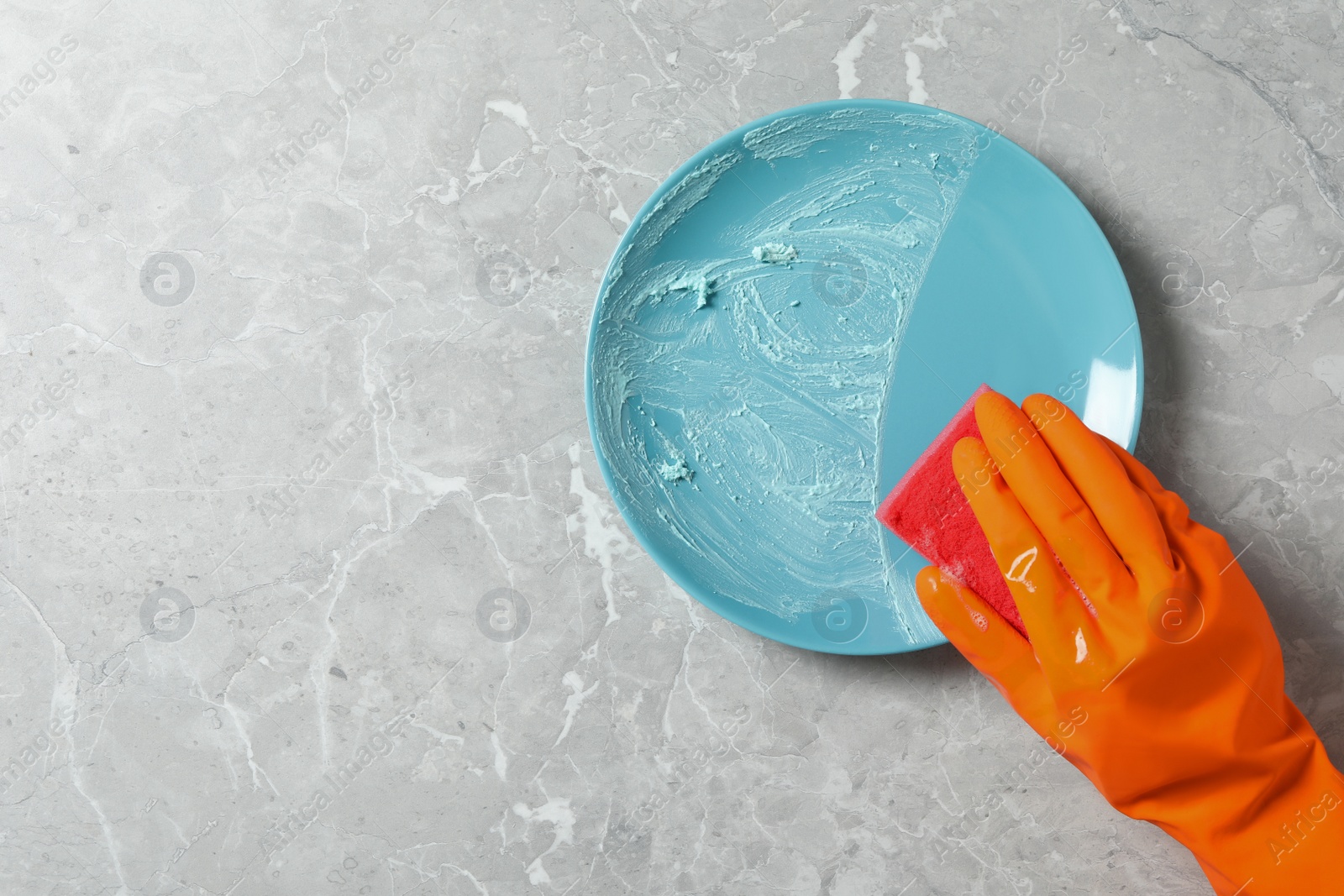 Photo of Woman washing dirty plate at grey marble table, top view. Space for text