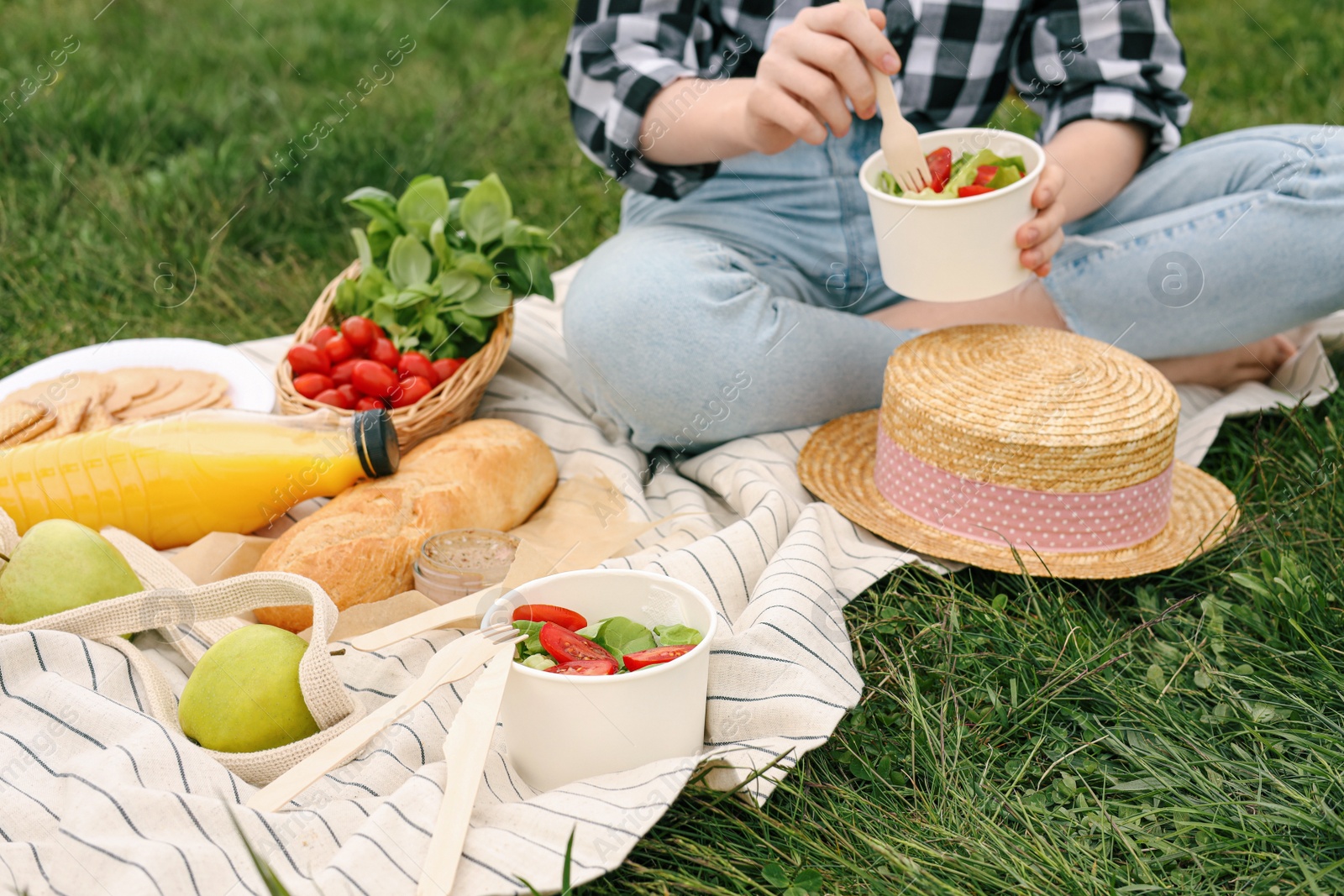 Photo of Girl having picnic on green grass in park, closeup