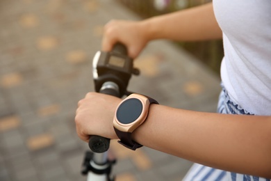 Photo of Woman with smartwatch and scooter outdoors, closeup