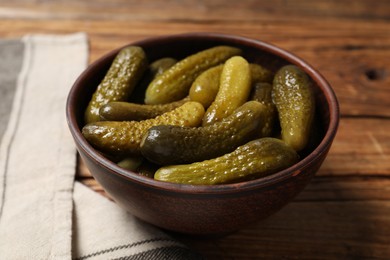 Tasty pickled cucumbers in bowl on wooden table