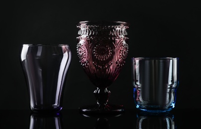 Photo of Set of different colorful empty glasses on black background