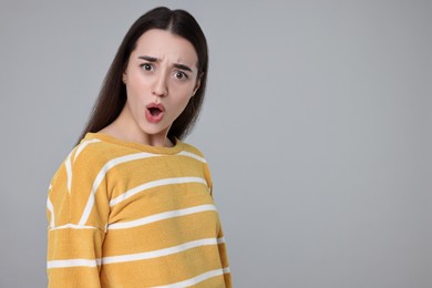 Portrait of surprised woman on grey background. Space for text
