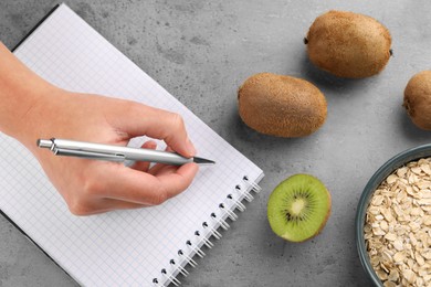 Photo of Woman developing diet plan at grey table with products, top view