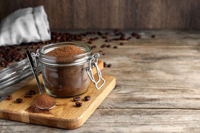 Glass jar of instant coffee and spoon on wooden table. Space for text