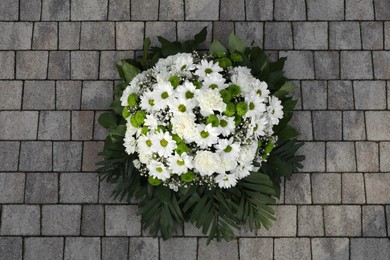 Photo of Funeral wreath of flowers on stone surface, top view