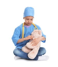 Cute child playing doctor with stuffed toy on white background