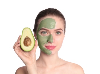 Young woman with clay mask on her face holding avocado against white background. Skin care