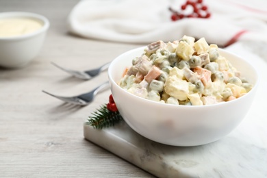 Traditional russian salad Olivier served on white wooden table