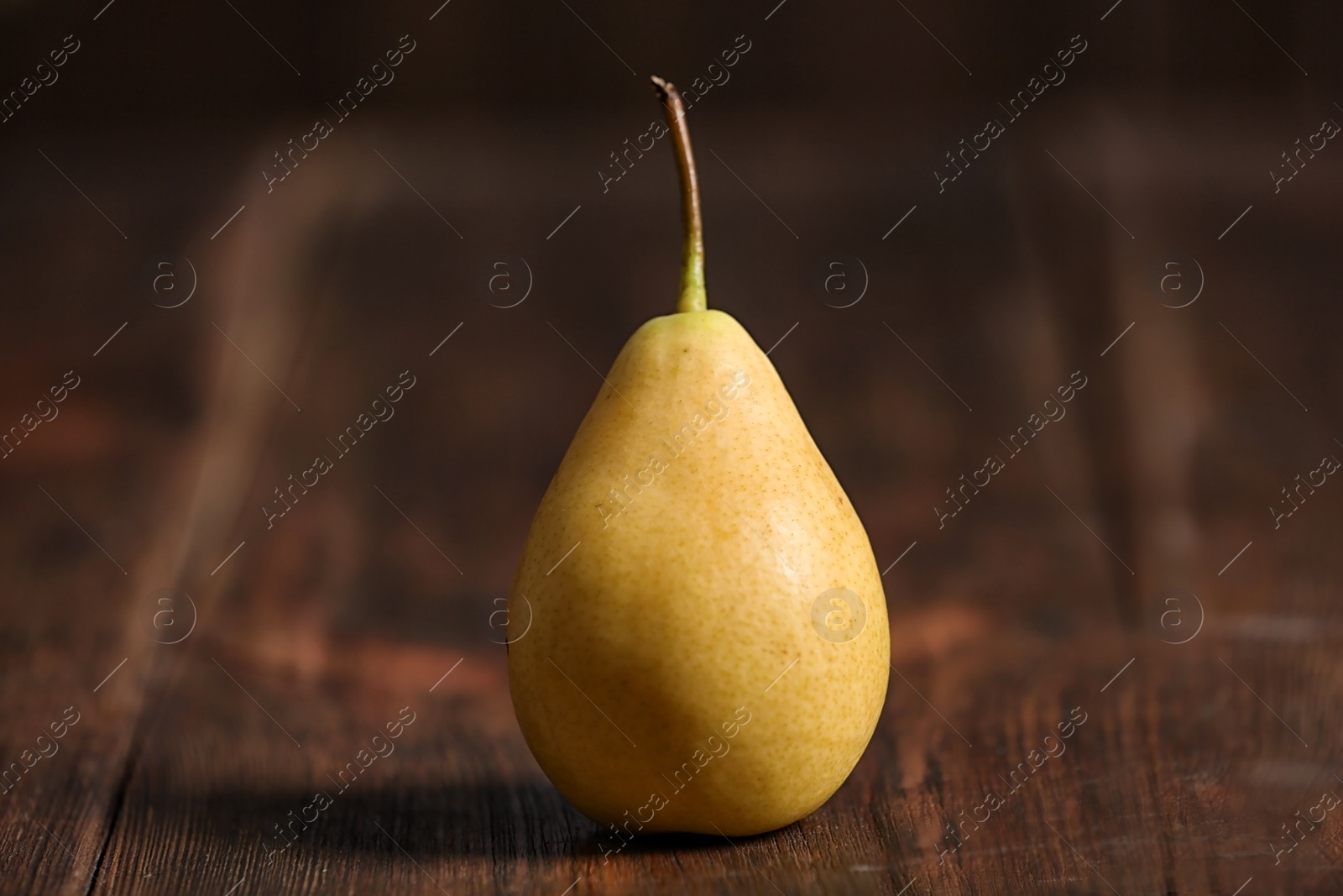 Photo of Tasty ripe yellow pear on wooden background