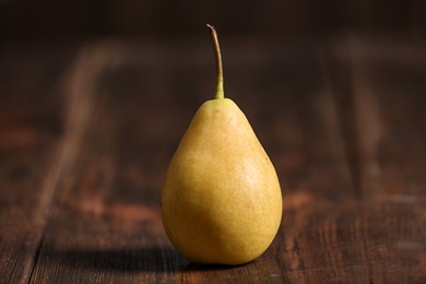 Photo of Tasty ripe yellow pear on wooden background