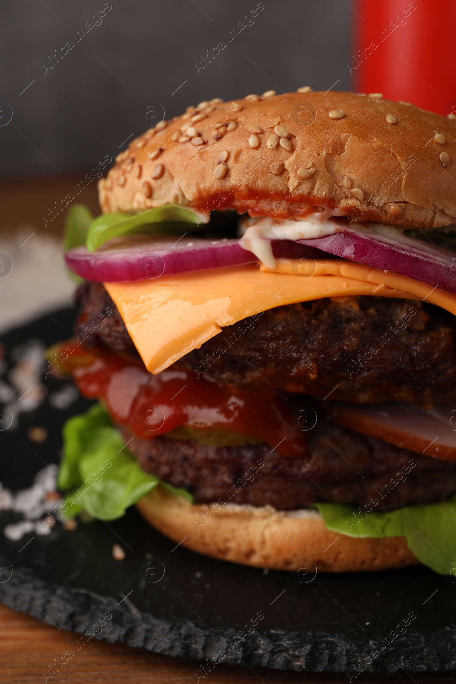 Photo of Tasty cheeseburger with patties on wooden table, closeup