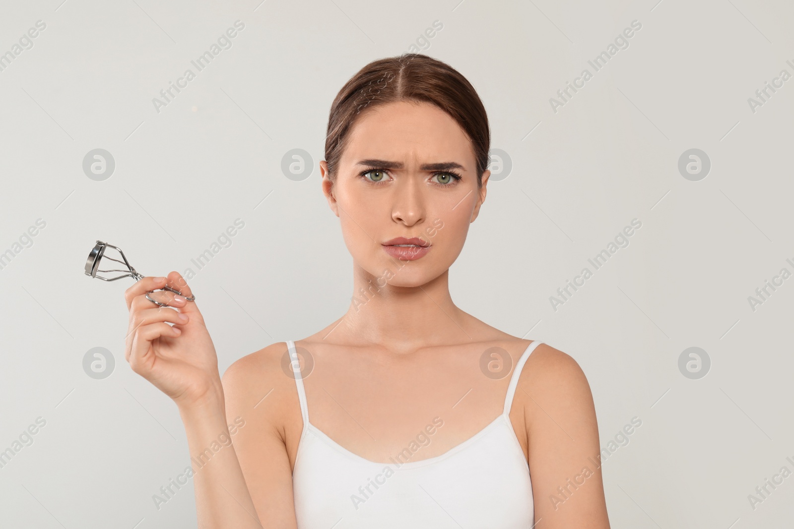 Photo of Emotional woman with eyelash curler on white background, space for text