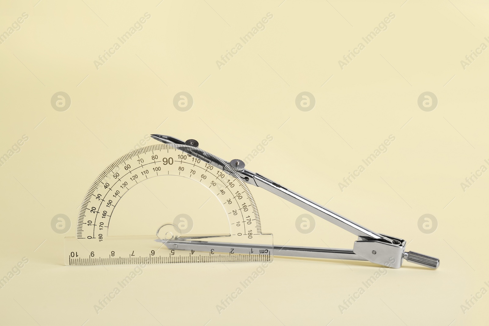Photo of Protractor and metal compass on yellow background