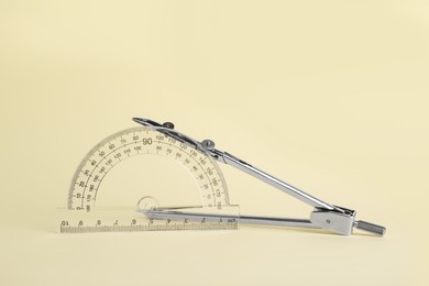Photo of Protractor and metal compass on yellow background