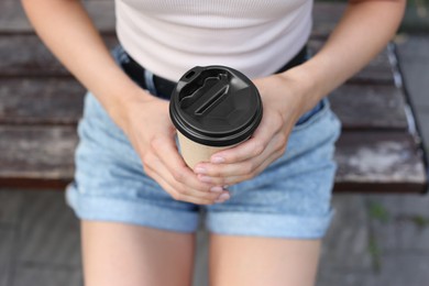 Coffee to go. Woman with paper cup of drink outdoors, closeup