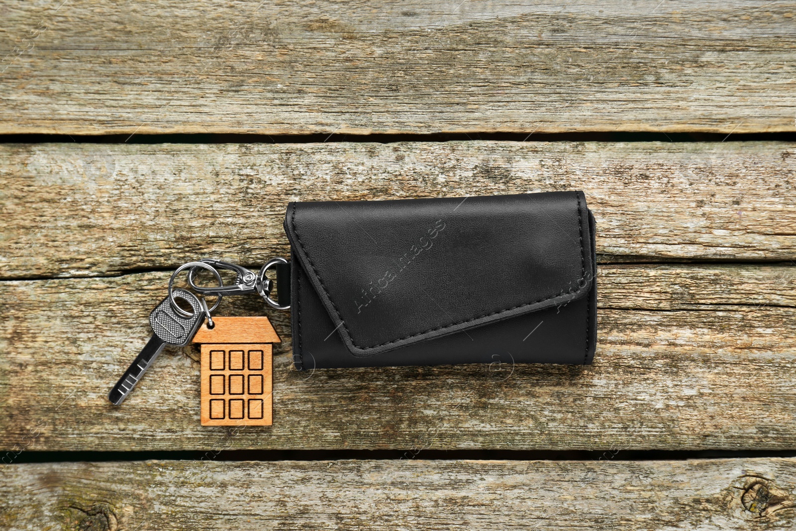 Photo of Leather case with key on old wooden table, top view