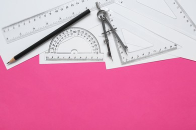 Photo of Different rulers, pencil and compass on pink background, flat lay. Space for text