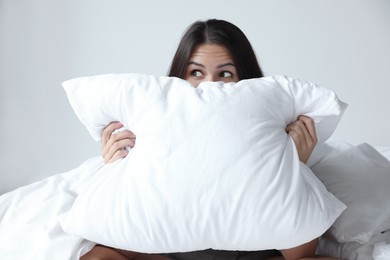 Young woman covering face with pillow in bedroom