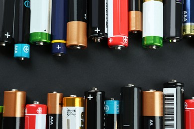 Image of Many different batteries on black background, flat lay