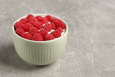 Bowl with delicious yogurt and raspberries on grey table, closeup. Space for text