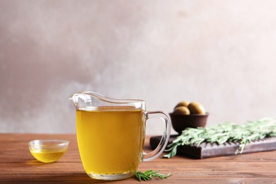 Photo of Jug with fresh rosemary oil on table