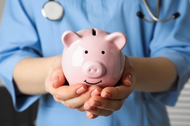 Photo of Doctor holding piggy bank in hands, closeup. Medical insurance