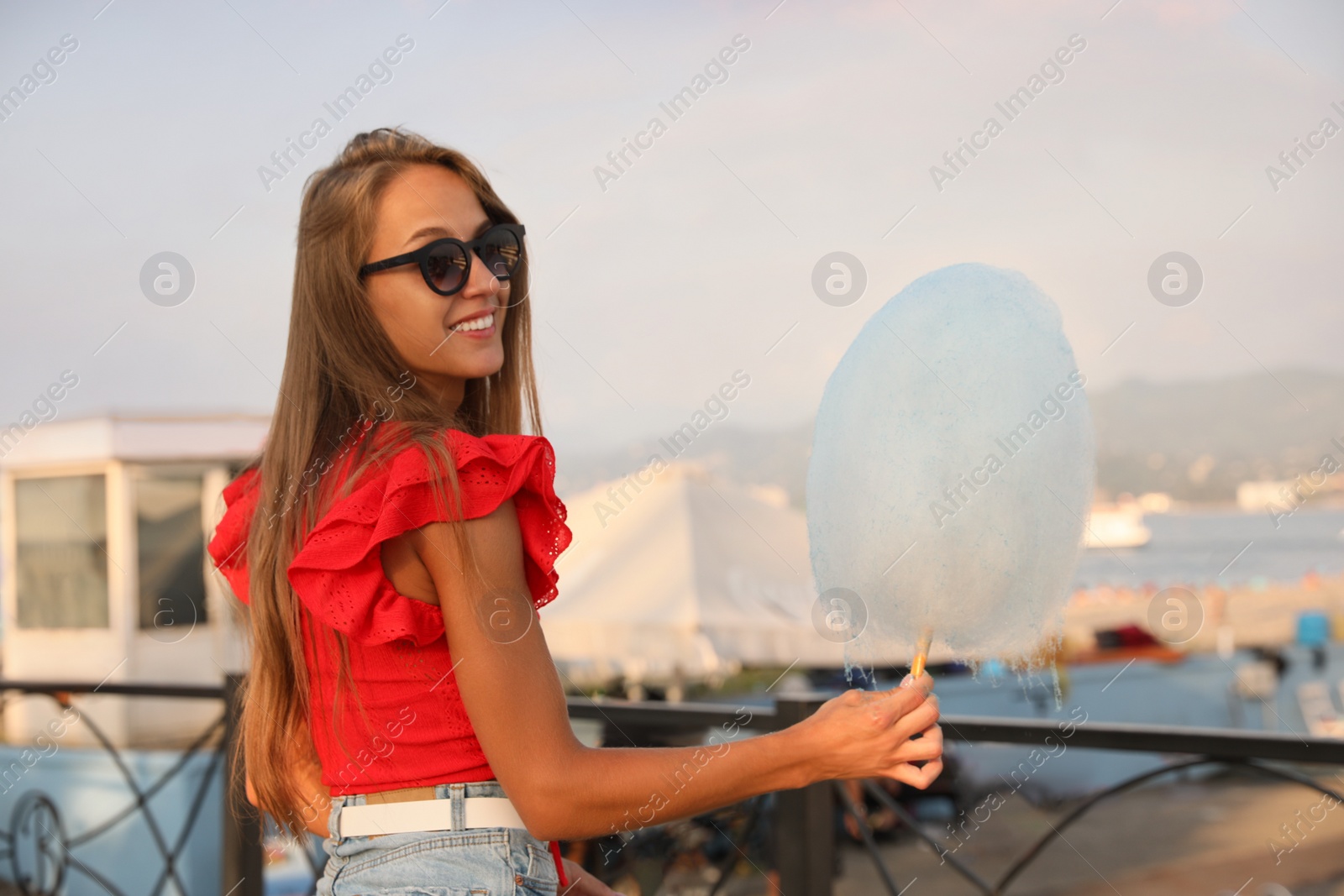 Photo of Pretty young woman with cotton candy outdoors