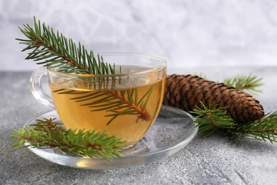Cup with delicious immunity boosting tea and fir on grey table, closeup