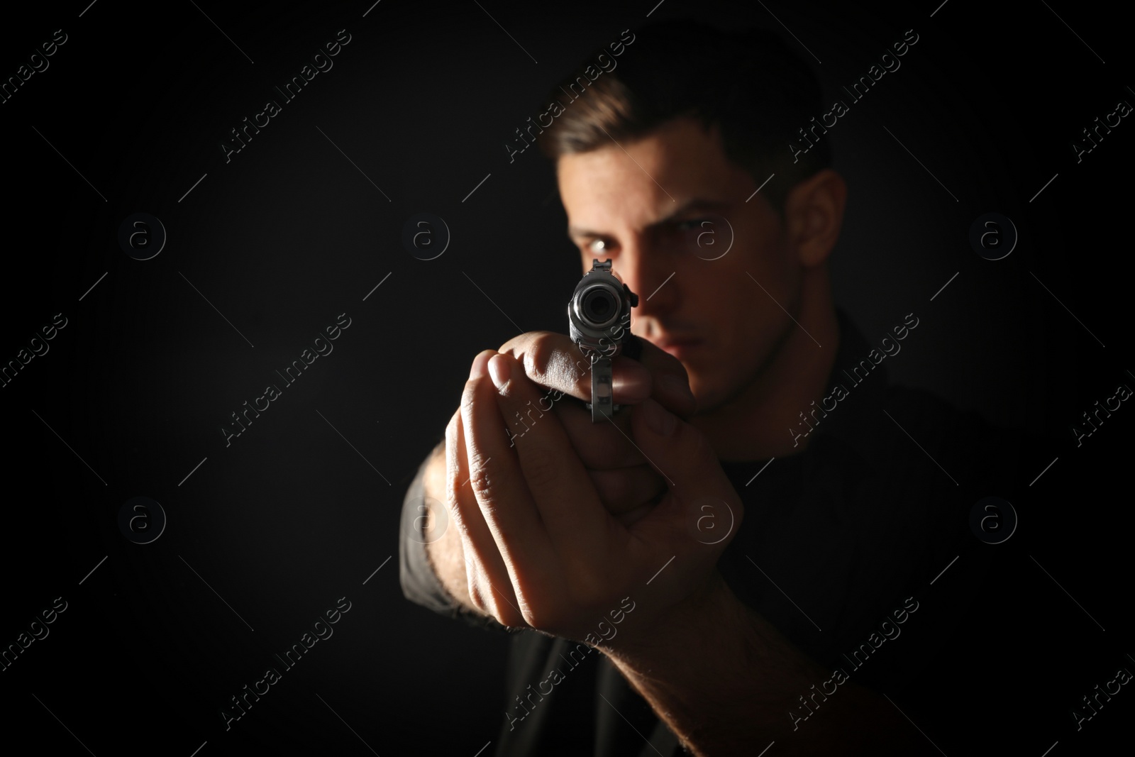 Photo of Professional killer with gun on black background