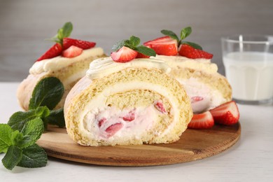 Photo of Delicious cake roll with strawberries and cream on wooden board, closeup