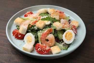 Photo of Delicious Caesar salad with shrimps on wooden table, closeup