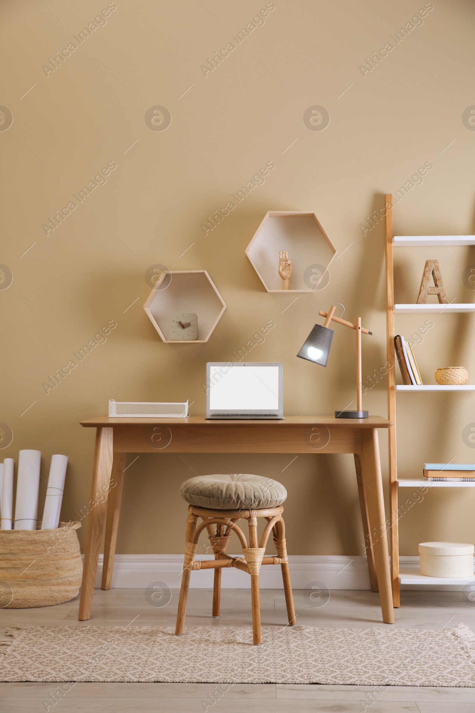 Photo of Comfortable wooden stool near table with laptop indoors. Interior design