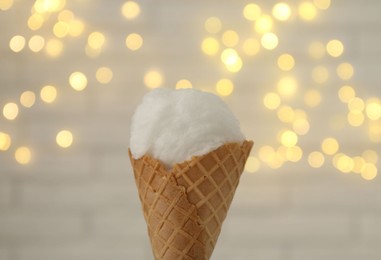 Cotton candy in waffle cone against blurred lights, closeup