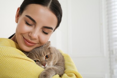 Woman with her adorable cat at home, space for text