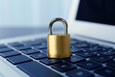 Photo of Metal padlock on laptop keyboard, closeup. Cyber security concept