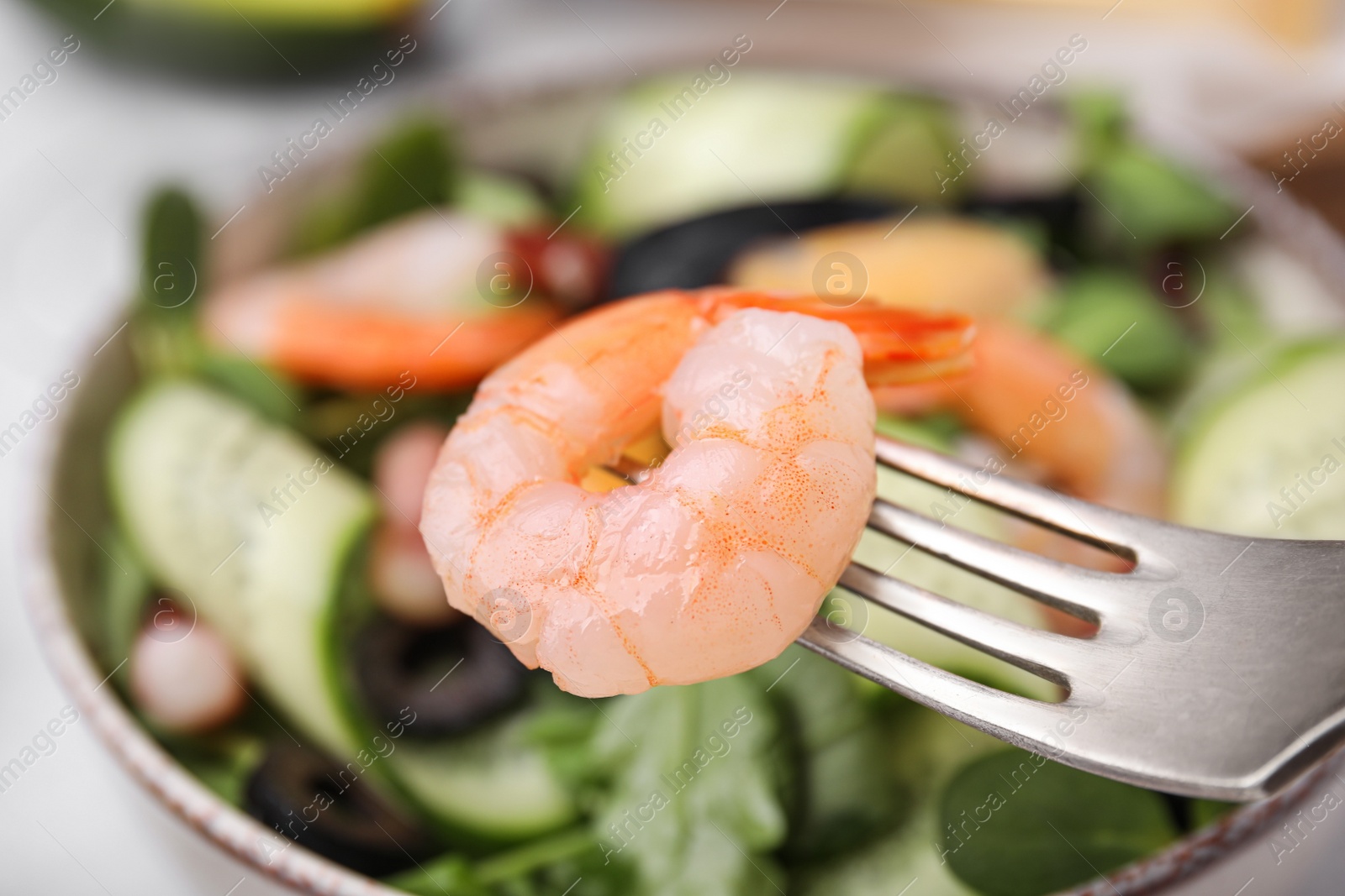 Photo of Fork with shrimp, closeup. Eating delicious seafood salad