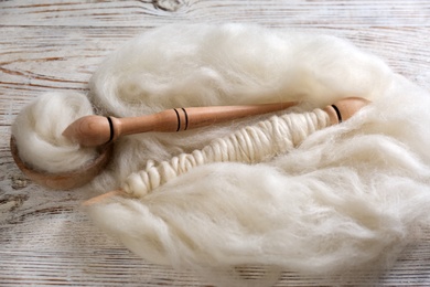 Soft wool and spindles on white wooden table, flat lay