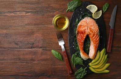 Photo of Tasty salmon with spinach served on wooden table, flat lay. Space for text