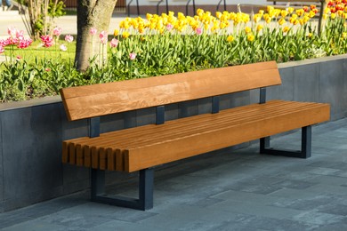 Photo of Wooden bench near flowerbed outdoors on sunny morning