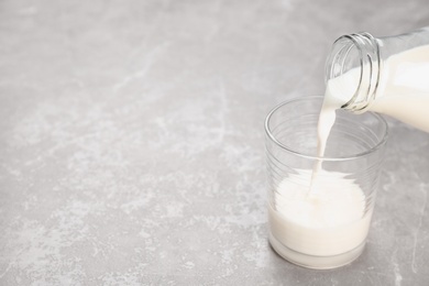 Pouring of milk from bottle into glass on table. Fresh dairy product