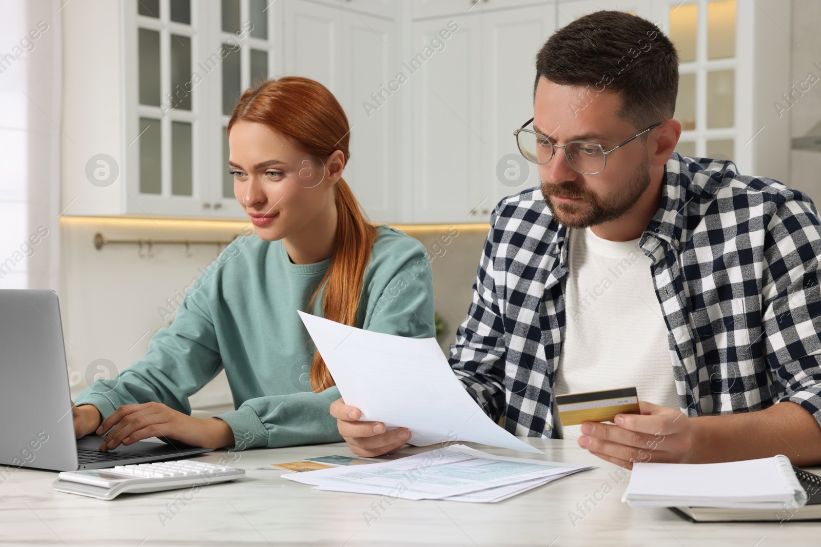 Photo of Couple with credit card using laptop for paying taxes online at home