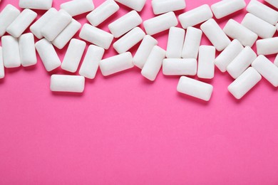 Tasty white chewing gums on pink background, flat lay. Space for text
