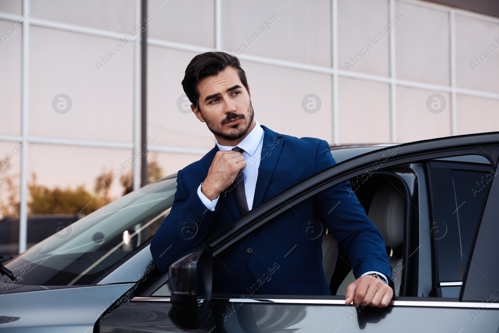 Photo of Attractive young man near luxury car outdoors