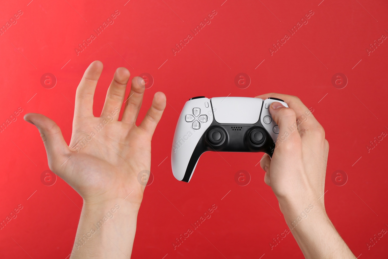 Photo of Man using wireless game controller on red background, closeup