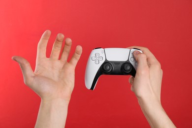 Man using wireless game controller on red background, closeup